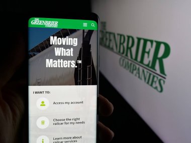 Stuttgart, Almanya - 10-30-2025: Demiryolu şirketi The Greenbrier Companies Inc. 'in internet sayfası ile cep telefonu tutan kişi logonun önünde ekranda. Telefon ekranının merkezine odaklan.