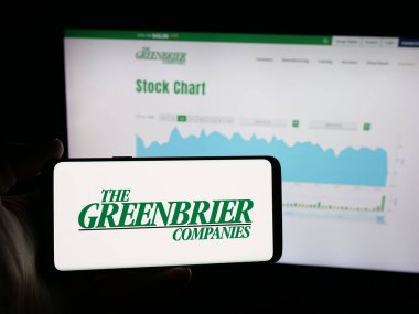 Stuttgart, Almanya - 10-30-2025: Demiryolu şirketi The Greenbrier Companies Inc. 'in logosunu elinde tutan kişi web sitesinin önünde ekranda. Telefon ekranına odaklan.