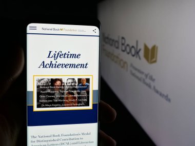 Stuttgart, Almanya - 10-30-2025: ABD Ulusal Kitap Vakfı 'nın web sayfası olan akıllı telefon sahibi kişi logonun önünde ekranda. Telefon ekranının merkezine odaklan.