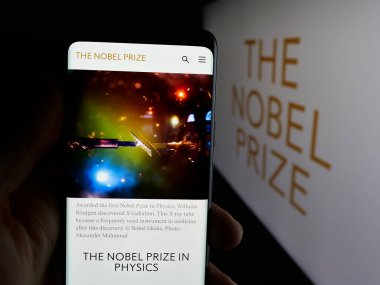 Stuttgart, Almanya - 10-30-2025: Logo önünde Nobel Ödülleri web sayfası bulunan cep telefonu sahibi kişi. Telefon ekranının merkezine odaklan.