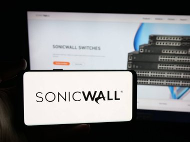 Stuttgart, Almanya - 10-30-2025: İnternet sitesinin önünde üzerinde ABD 'li siber güvenlik şirketi SonicWall Inc.' in logosu olan akıllı telefonu tutan kişi. Telefon ekranına odaklan.