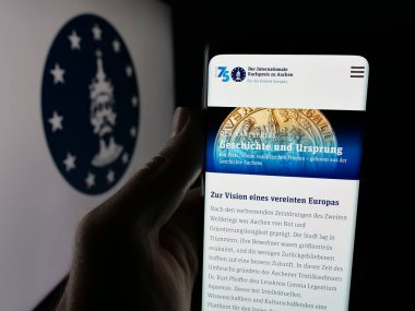 Stuttgart, Almanya - 10-30-2025: Logonun önünde ekranda Karlspreis zu Aachen (Charlemagne Ödülü) web sayfası olan akıllı telefon sahibi kişi. Telefon ekranının merkezine odaklan.