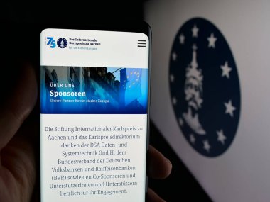 Stuttgart, Almanya - 10-30-2025: Logonun önünde ekranda Karlspreis zu Aachen (Charlemagne Ödülü) web sayfası bulunan kişi. Telefon ekranının merkezine odaklan.