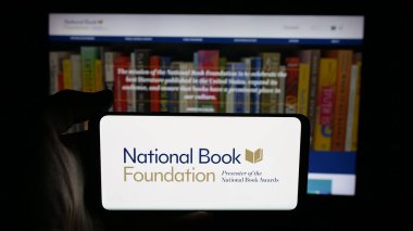 Stuttgart, Almanya - 10-30-2025: Web sayfası önünde ekranda ABD 'li Ulusal Kitap Vakfı logosu bulunan kişi. Telefon ekranına odaklan.
