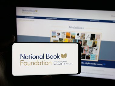 Stuttgart, Almanya - 10-30-2025: Web sitesi önünde ekranda ABD 'li Ulusal Kitap Vakfı logosu bulunan kişi. Telefon ekranına odaklan.