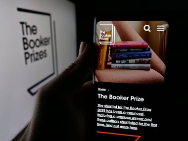 Stuttgart, Almanya - 10-30-2025: İngiliz Edebiyat Ödülü Booker Ödülü 'nün web sayfası logonun önünde duran kişi. Telefon ekranının merkezine odaklan.