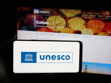 Stuttgart, Almanya - 10-31-2025: Birleşmiş Milletler organizasyonu UNESCO logosuna sahip akıllı telefonu web sitesi önünde ekranda tutan kişi. Telefon ekranına odaklan.