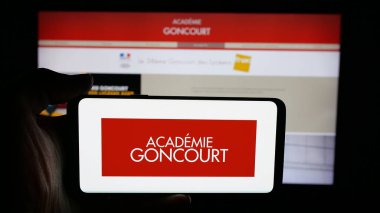 Stuttgart, Almanya - 10-31-2025: Fransız örgütü Academie Goncourt 'un logosunun bulunduğu cep telefonu web sayfası önünde ekranda. Telefon ekranına odaklan.