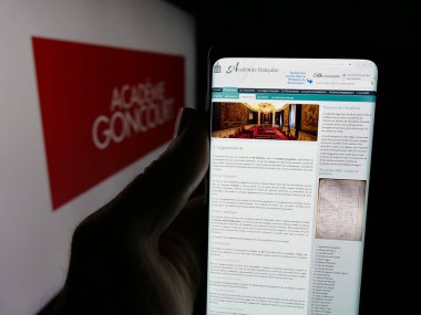 Stuttgart, Almanya - 10-31-2025: Fransız Akademi Goncourt 'un web sitesi ile akıllı telefonu logo önünde ekranda tutan kişi. Telefon ekranının merkezine odaklan.