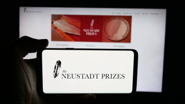 Stuttgart, Almanya - 10-31-2025: Cep telefonunda Neustadt Uluslararası Edebiyat Ödülü logosu olan kişi web sayfası önünde ekranda. Telefon ekranına odaklan.