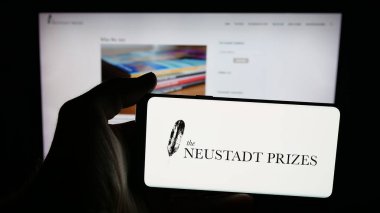 Stuttgart, Almanya - 10-31-2025: İnternet sayfasının önünde ekranda Neustadt Uluslararası Edebiyat Ödülü logosu bulunan cep telefonu sahibi kişi. Telefon ekranına odaklan.