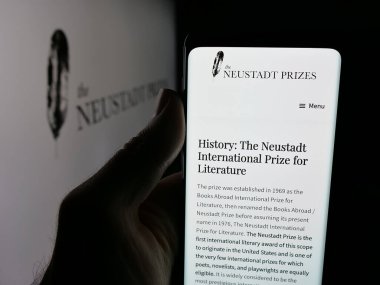 Stuttgart, Almanya - 10-31-2025: Logonun önünde ekranda Neustadt International Prize for Literature web sayfası ile akıllı telefon tutan kişi. Telefon ekranının merkezine odaklan.