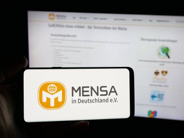 Stuttgart, Almanya - 10-31-2025: Deutschland E.V. 'de dahi toplum mensası logosu olan akıllı telefon sahibi kişi. Web sitesinin önünde ekranda. Telefon ekranına odaklan.