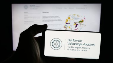 Stuttgart, Almanya - 10-31-2025: İnternet sayfası önünde Norveç Bilim ve Edebiyat Akademisi logosu bulunan cep telefonu sahibi kişi. Telefon ekranına odaklan.