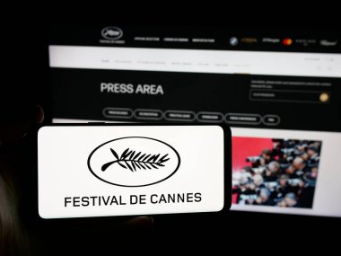 Stuttgart, Almanya - 10-31-2025: Cannes Film Festivali uluslararası etkinlik logosu içeren akıllı telefonu web sitesi önünde tutan kişi. Telefon ekranına odaklan.