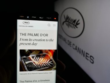 Stuttgart, Almanya - 10-31-2025: Uluslararası etkinlik Cannes Film Festivali 'nin web sayfası bulunan cep telefonu logosu önünde ekranda. Telefon ekranının merkezine odaklan.