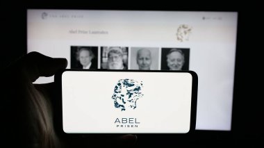 Stuttgart, Almanya - 10-31-2025: Web sayfası önünde üzerinde matematik ödülü logosu olan cep telefonu sahibi kişi. Telefon ekranına odaklan.