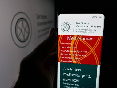 Stuttgart, Almanya - 10-31-2025: Norveç Bilim ve Edebiyat Akademisi 'nin web sayfası logonun önünde duran kişi. Telefon ekranının merkezine odaklan.