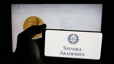 Stuttgart, Almanya - 10-31-2025: Web sayfası önünde Svenska Akademien (İsveç Akademisi) logosu olan cep telefonu sahibi kişi. Telefon ekranına odaklan.