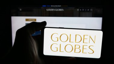 Stuttgart, Almanya - 10-31-2025: İnternet sayfası önünde üzerinde ABD televizyon ödülü logosu olan cep telefonu sahibi kişi Altın Küre Ödülü ekranda. Telefon ekranına odaklan.