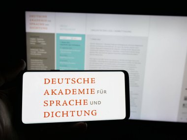 Stuttgart, Almanya - 11-01-2025: Web sitesi önünde ekranda Deutsche Akademie fuer Sprache und Dichtung logosu bulunan kişi. Telefon ekranına odaklan.