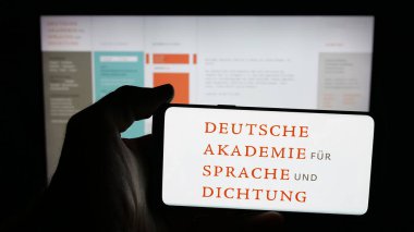 Stuttgart, Almanya - 11-01-2025: Web sayfasının önünde ekranda Deutsche Akademie fuer Sprache und Dichtung logosu bulunan cep telefonu sahibi kişi. Telefon ekranına odaklan.