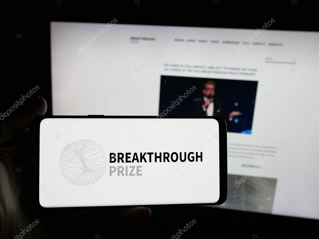 Stuttgart, Germany - 10-31-2025: Person holding smartphone with logo of international awards Breakthrough Prizes on screen in front of website. Focus on phone display.