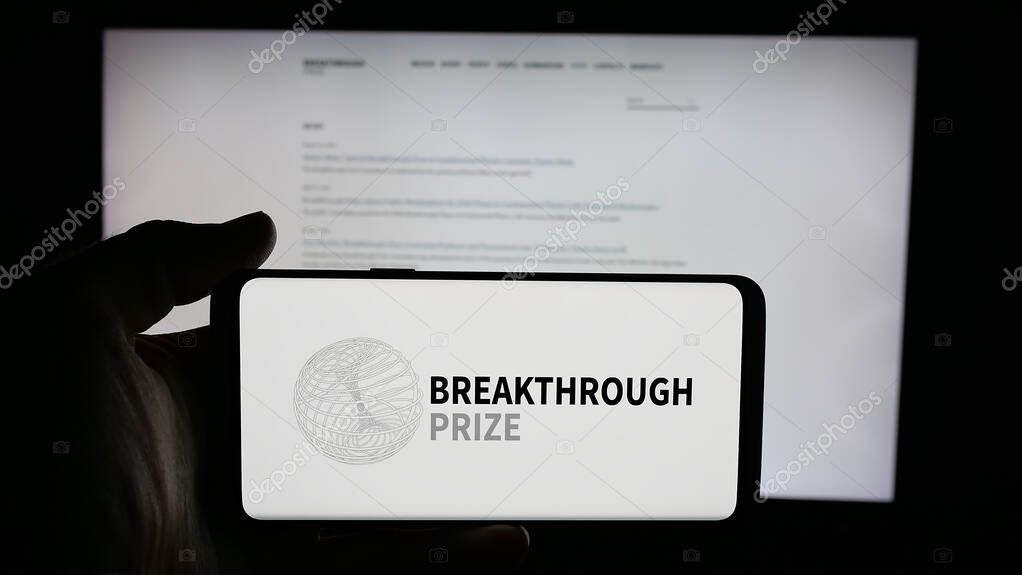 Stuttgart, Germany - 10-31-2025: Person holding cellphone with logo of international awards Breakthrough Prizes on screen in front of webpage. Focus on phone display.