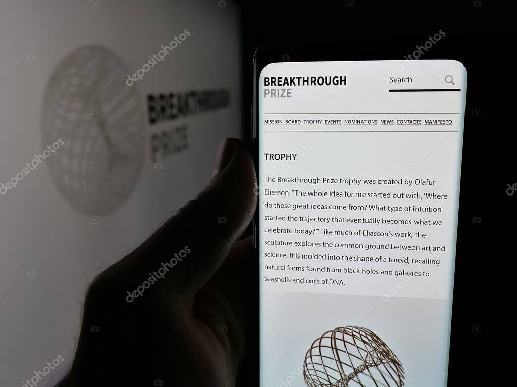 Stuttgart, Germany - 10-31-2025: Person holding smartphone with web page of international awards Breakthrough Prizes on screen in front of logo. Focus on center of phone display.