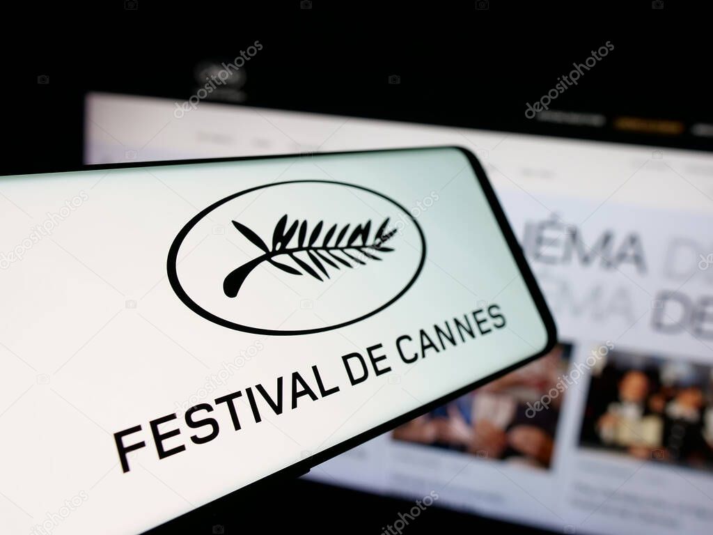 Stuttgart, Germany - 10-31-2025: Smartphone with logo of international event Cannes Film Festival on screen in front of website. Focus on center-left of phone display.