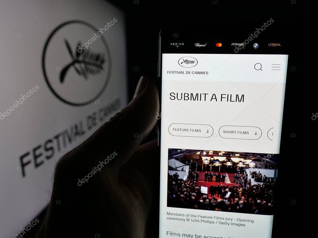 Stuttgart, Germany - 10-31-2025: Person holding smartphone with web page of international event Cannes Film Festival on screen in front of logo. Focus on center of phone display.