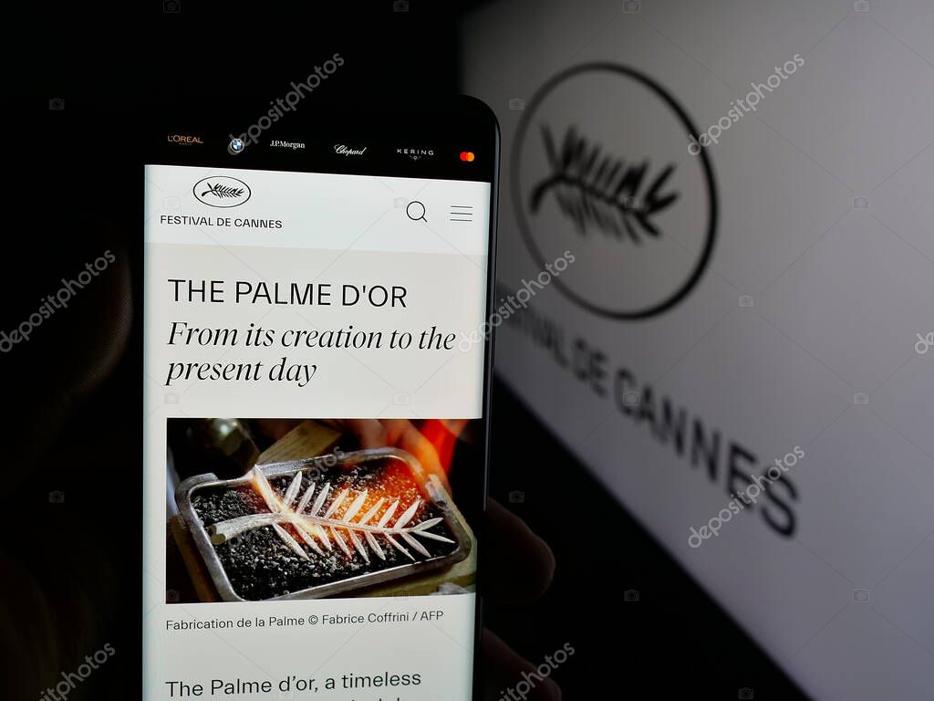 Stuttgart, Germany - 10-31-2025: Person holding cellphone with webpage of international event Cannes Film Festival on screen in front of logo. Focus on center of phone display.