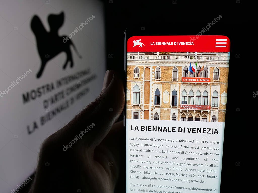Stuttgart, Germany - 10-31-2025: Person holding smartphone with web page of Venice Film Festival (Biennale) on screen in front of logo. Focus on center of phone display.