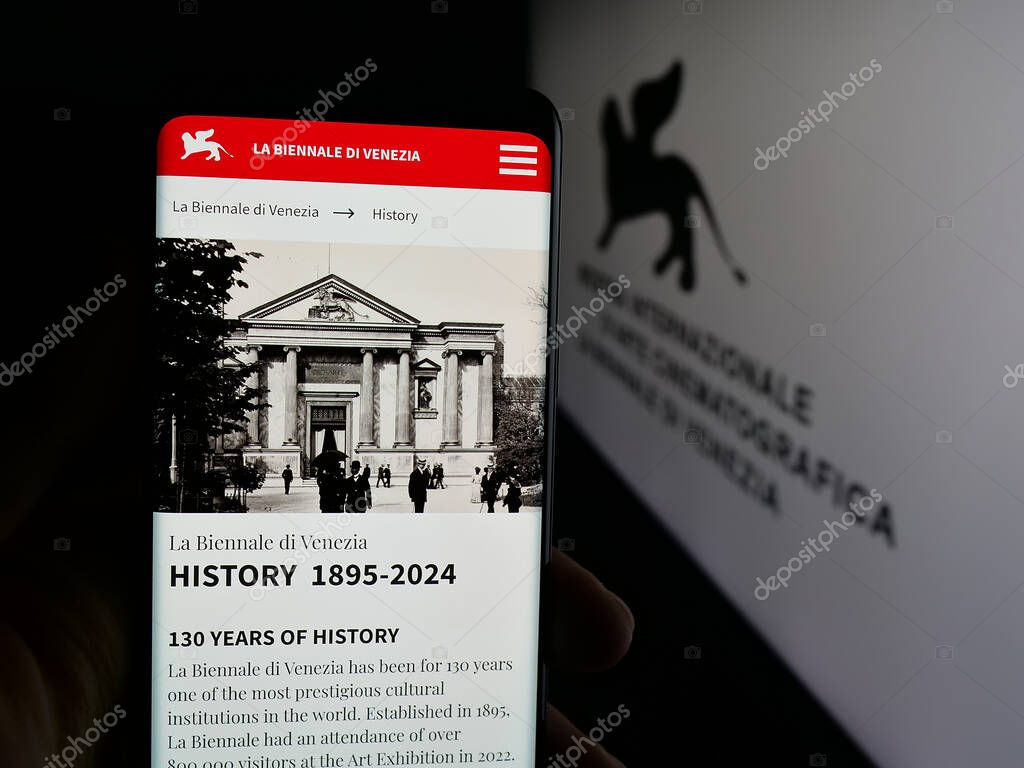 Stuttgart, Germany - 10-31-2025: Person holding cellphone with webpage of Venice Film Festival (Biennale) on screen in front of logo. Focus on center of phone display.