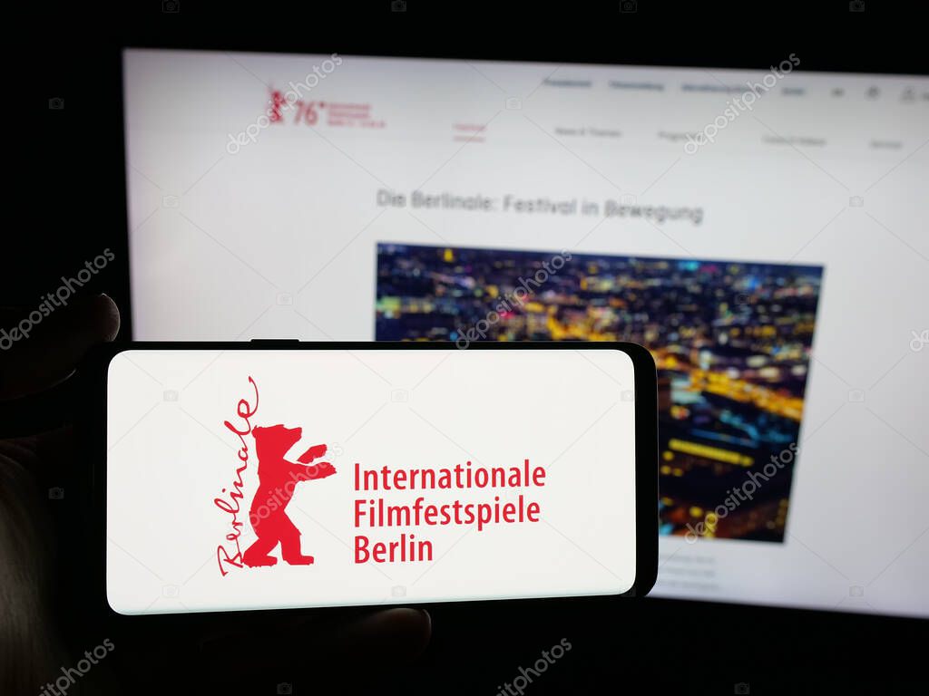 Stuttgart, Germany - 10-31-2025: Person holding smartphone with logo of Berlin International Film Festival Berlinale on screen in front of website. Focus on phone display.