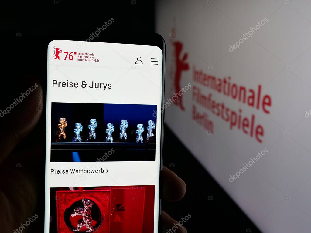 Stuttgart, Germany - 10-31-2025: Person holding smartphone with web page of Berlin International Film Festival Berlinale on screen in front of logo. Focus on center of phone display.