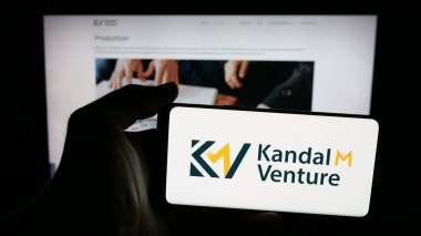 Stuttgart, Almanya - 11-02-2025: El çantası şirketi Kandal M Venture Limited 'in logosuna sahip cep telefonu sahibi kişi web sayfasının önünde ekranda. Telefon ekranına odaklan.