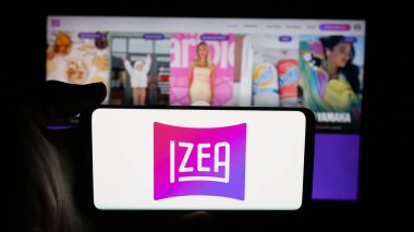 Stuttgart, Almanya - 11-02-2025: İnternet sayfası önünde IZEA Worldwide Inc. 'in logosunun bulunduğu cep telefonu sahibi kişi. Telefon ekranına odaklan.
