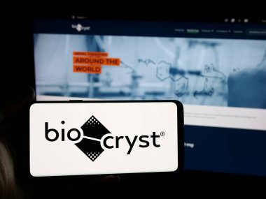Stuttgart, Germany - 11-03-2025: Person holding smartphone with logo of US company BioCryst Pharmaceuticals Inc. on screen in front of website. Focus on phone display.