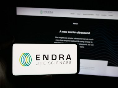 Stuttgart, Germany - 11-03-2025: Person holding smartphone with logo of ultrasound company ENDRA Life Sciences Inc. on screen in front of website. Focus on phone display.