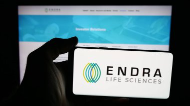 Stuttgart, Germany - 11-03-2025: Person holding mobile phone with logo of ultrasound company ENDRA Life Sciences Inc. on screen in front of web page. Focus on phone display.
