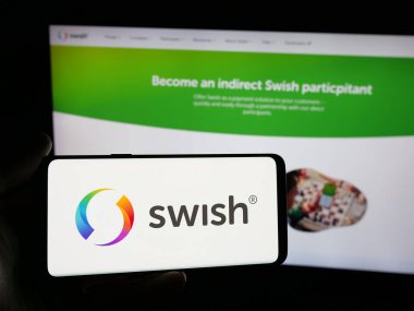 Stuttgart, Germany - 11-03-2025: Person holding smartphone with logo of Swedish fintech company Swish (Getswish AB) on screen in front of website. Focus on phone display.