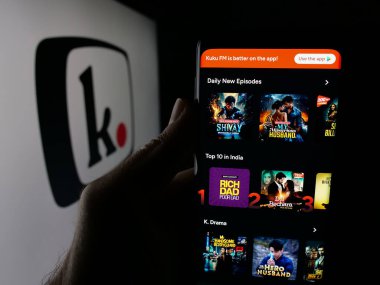 Stuttgart, Germany - 11-03-2025: Person holding cellphone with webpage of Indian platform company Kuku FM (kukufm.com) on screen in front of logo. Focus on center of phone display.