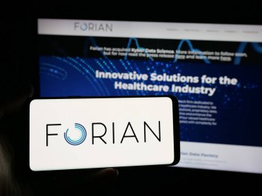 Stuttgart, Germany - 11-03-2025: Person holding smartphone with logo of US software company Forian Inc. on screen in front of website. Focus on phone display.