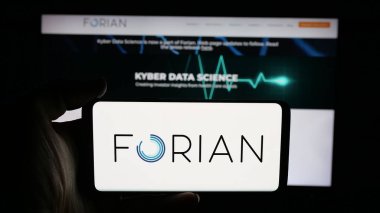 Stuttgart, Germany - 11-03-2025: Person holding cellphone with logo of US software company Forian Inc. on screen in front of webpage. Focus on phone display.