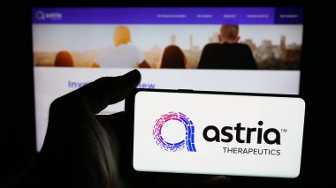 Stuttgart, Germany - 11-03-2025: Person holding mobile phone with logo of US pharma company Astria Therapeutics Inc. on screen in front of web page. Focus on phone display.
