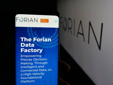 Stuttgart, Germany - 11-03-2025: Person holding smartphone with web page of US software company Forian Inc. on screen in front of logo. Focus on center of phone display.