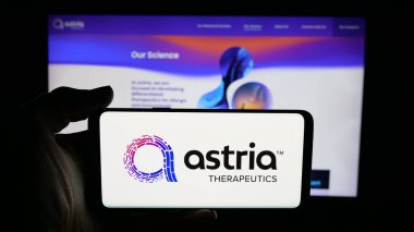Stuttgart, Germany - 11-03-2025: Person holding cellphone with logo of US pharma company Astria Therapeutics Inc. on screen in front of webpage. Focus on phone display.