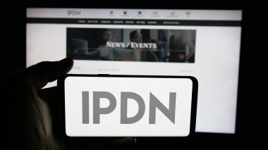 Stuttgart, Germany - 11-04-2025: Person holding cellphone with logo of Professional Diversity Network Inc. (IPDN) on screen in front of webpage. Focus on phone display.