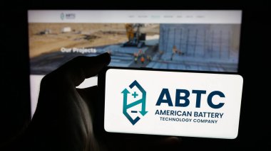 Stuttgart, Germany - 11-04-2025: Person holding mobile phone with logo of American Battery Technology Company (ABTC) on screen in front of web page. Focus on phone display.